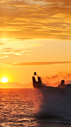 Boat crashing against waves in Alaska at sunset